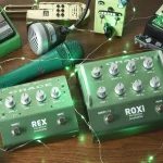 Green Grace Design REX and ROXi microphone preamplifier pedals surrounded by fairy lights and vintage gear on a wood surface.