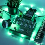 Grace Design ROXi acoustic microphone preamp pedal illuminated with green stage lighting on a performance setup.